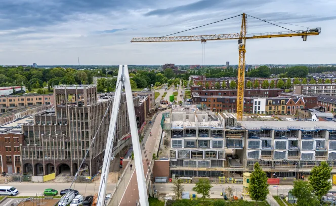 Nieuwbouw in de stad met een hijskraan en brug op de voorgrond